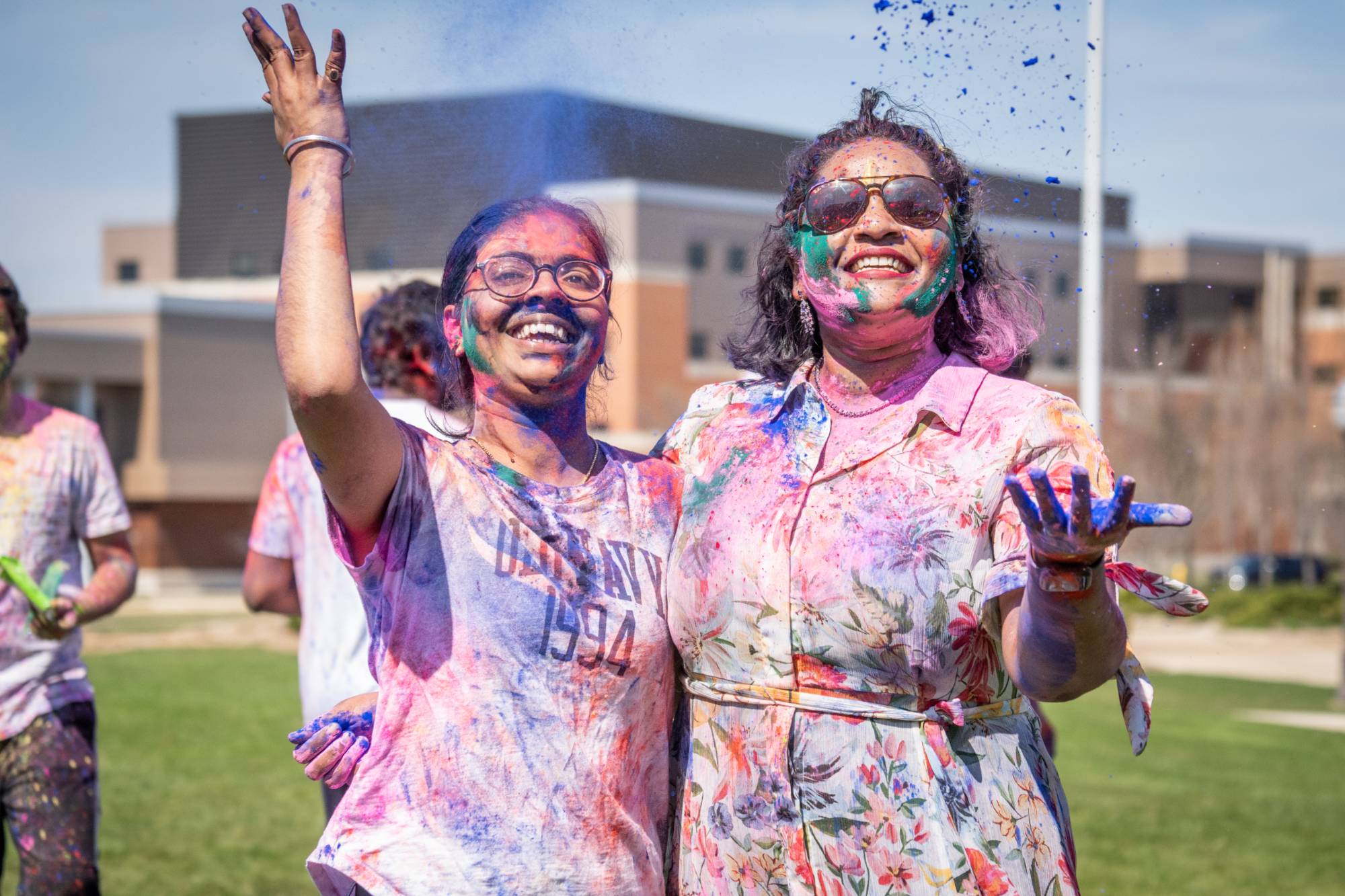 Two smiling students covered in multicolored dye